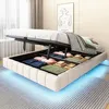 A bed with its storage compartment open, revealing neatly folded linens and towels. The bed frame has subtle LED lighting underneath. Náhľad obrázku produktu