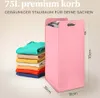 A pink laundry basket with clothes inside and a stack of folded clothes next to it, with dimensions indicated. Anteprima dell’immagine prodotto