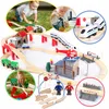 A collage of images showing a wooden train set with various accessories, including buildings, figures, and track pieces, being played with by children. Náhled obrázku produktu