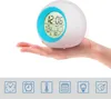 A hand holding a digital alarm clock with a light-up display. Produktbild-Vorschau