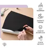 Hands peeling off a black felt material from a white backing, with scissors in the background. Produktbild-Vorschau