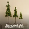 Three artificial Christmas trees of varying sizes, decorated with string lights, are displayed on a mantelpiece. Produktbild-Vorschau