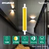 A product shot of a Sylvania LED light bulb with marketing icons and text overlaid on a background of a staircase with wall lights. Produktbild-Vorschau