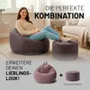 A woman is sitting on a large beanbag chair in a living room setting, with a smaller ottoman next to her. Below, there are two smaller beanbag-like items, one larger than the other, with a plus sign between them, suggesting a bundle or combination. Voir les images du produit