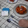A table setting with cutlery, food, and a travel cutlery holder. Produktbild-Vorschau