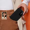 A person is holding a black phone case with a transparent window, which is partially inserted into their pocket. A phone screen showing an incoming call is visible in the pocket. Náhled obrázku produktu