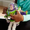 A child's hands are interacting with a Buzz Lightyear action figure. Voir les images du produit