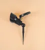 A black solar-powered spotlight with a stake is shown against a plain, light orange background. Produktbild-Vorschau