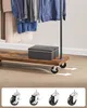 A close-up shot of a rolling garment rack with clothes hanging on it and a storage box on the bottom shelf. Four casters are displayed at the bottom of the image. Náhled obrázku produktu