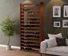 A wooden wine rack filled with wine bottles, placed next to a potted plant and a sofa with pillows, in a room with framed pictures on the wall. Produktbild-Vorschau