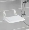 A white folding shower seat mounted on a tiled wall next to a shower head. Produktbild-Vorschau