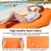A woman relaxing on an orange inflatable air bed on a beach. Produktbild-Vorschau