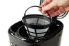 A hand holds a coffee filter basket over a coffee maker. Náhled obrázku produktu