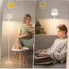 A split image showing two people using a floor lamp in different settings. Podgląd zdjęcia produktu