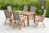 A wooden garden table and chairs set on a patio with greenery in the background. Náhled obrázku produktu