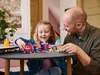 A father and daughter are playing with a LEGO set at a table. Produktbild-Vorschau