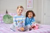 Two young girls sitting on a bed, holding toys. Produktbild-Vorschau