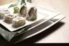 Sushi rolls and wasabi on a white plate, with green leaves, on a wooden surface. Náhled obrázku produktu
