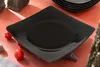 A black square plate is placed on an orange surface, with rocks and cherry tomatoes around it. Podgląd zdjęcia produktu