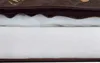 A close-up view of the layered material of a dog bed, showing the brown outer fabric and white filling. Náhled obrázku produktu