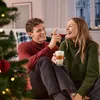 A couple is sitting on the floor next to a Christmas tree, laughing and holding a drink. Podgląd zdjęcia produktu