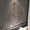 A modern, minimalist wall clock with a gold metal frame and brown hands is mounted on a gray wall. Anteprima dell’immagine prodotto
