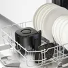 A black air fryer basket and accessories are placed in a dishwasher rack alongside white plates. Produktbild-Vorschau