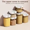 A hand is stacking clear food storage containers filled with various dry goods. Produktbild-Vorschau