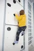A child is climbing on an indoor climbing wall in a room. Anteprima dell’immagine prodotto