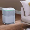 An air purifier is placed on a wooden floor next to a sofa in a living room. Náhled obrázku produktu