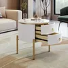 A round white side table with gold legs and handles, featuring two open drawers, is placed on a patterned rug next to a beige sofa in a living room setting. Anteprima dell’immagine prodotto
