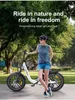 A woman stands next to an electric bicycle in a park-like setting. Produktbild-Vorschau