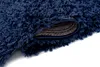 A close-up, angled view of a dark blue shaggy rug, with a corner lifted to show the backing. Anteprima dell’immagine prodotto