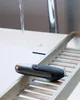 A hair trimmer is placed on a wooden tray next to a sink with water running. Produktbild-Vorschau