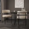 Two beige upholstered chairs with black metal legs are placed around a dark dining table in a modern room setting. Produktbild-Vorschau