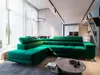 A modern living room with a large green sectional sofa, a coffee table, and a dining area in the background. Produktbild-Vorschau