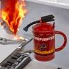 A firefighter-themed mug is placed on a stove with flames, suggesting a playful or thematic context. Produktbild-Vorschau