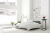 A bedroom scene with a bed, a large window overlooking a snowy landscape, and a small black side table with a vase of pink roses. Voir les images du produit