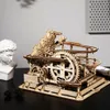 A wooden marble run model with gears and tracks, placed on a dark surface next to a white bust. Náhľad obrázku produktu