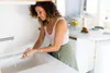 A woman is washing her hands in a kitchen sink. Náhľad obrázku produktu