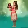 A young girl dressed as Moana holds a Moana doll. Voir les images du produit