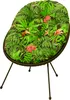 A round chair cushion with a tropical leaf and flower pattern, supported by three thin black legs. Produktbild-Vorschau