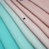 A close-up, diagonal view of folded fabric panels in shades of pink and blue, with small black star cutouts visible on some panels. Náhled obrázku produktu