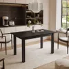 A black dining table with a vase and a book on it, set in a modern dining room with white cabinets and a window view. Produktbild-Vorschau