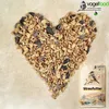 A heart shape made of birdseed with a bag of birdseed in the lower right corner. Produktbild-Vorschau