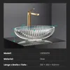 A clear glass basin with a gold faucet is displayed on a black surface against a gray background, with dimensions indicated by lines and numbers. Podgląd zdjęcia produktu