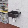 A black sink mounted on a concrete wall in a garage or workshop setting, with storage bins and tools visible. Podgląd zdjęcia produktu
