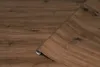 A roll of wood-effect adhesive film is shown partially unrolled on a surface with a similar wood grain pattern. Voir les images du produit