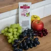 A product packaging for yeast and nutrient for winemaking, displayed with fresh fruits like apples and grapes, and berries, on a wooden surface. Produktbild-Vorschau