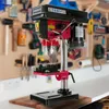 A red and black AREBOS table drill press is shown in a workshop setting with tools on the wall in the background. Produktbild-Vorschau